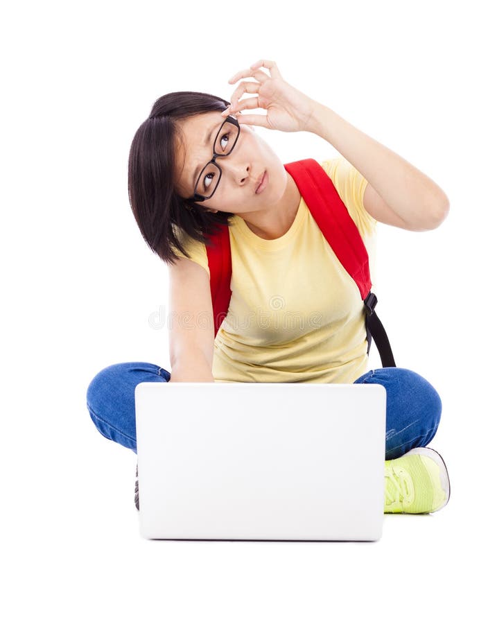 Giovane ragazza contestata dello studente che si siede sul pavimento con un computer portatile fotografia stock libera da diritti Giovane ragazza contestata dello studente che si siede sul pavimento con un computer portatile fotografia stock libera da diritti