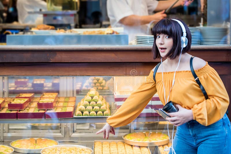 Beautiful young girl in fashionable clothes shows traditional Turkish dessert Baklava at display in Turkey. Beautiful young girl in fashionable clothes shows traditional Turkish dessert Baklava at display in Turkey