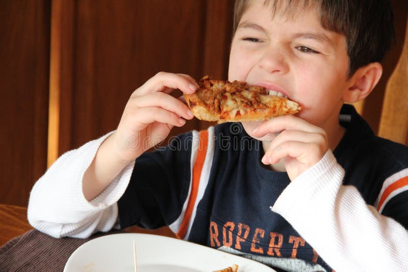 Giovane ragazzo che mangia pizza fotografia stock libera da diritti Giovane ragazzo che mangia pizza fotografia stock libera da diritti