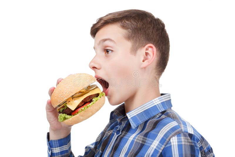 Giovane ragazzo che tiene un hamburger ed aperto la sua bocca per mangiare fotografia stock libera da diritti Giovane ragazzo che tiene un hamburger ed aperto la sua bocca per mangiare fotografia stock libera da diritti
