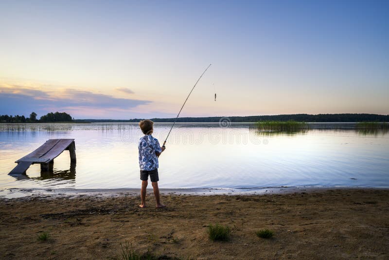 Giovane ragazzo lettone che pesca nel lago Juglas al tramonto, Lettonia, Riga, Lettonia, Europa fotografie stock Giovane ragazzo lettone che pesca nel lago Juglas al tramonto, Lettonia, Riga, Lettonia, Europa fotografie stock