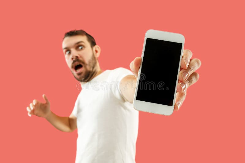Giovane schermo bello dello smartphone di rappresentazione dell'uomo isolato su fondo di corallo nella scossa con un fronte di so fotografie stock libere da diritti Giovane schermo bello dello smartphone di rappresentazione dell'uomo isolato su fondo di corallo nella scossa con un fronte di so fotografie stock libere da diritti