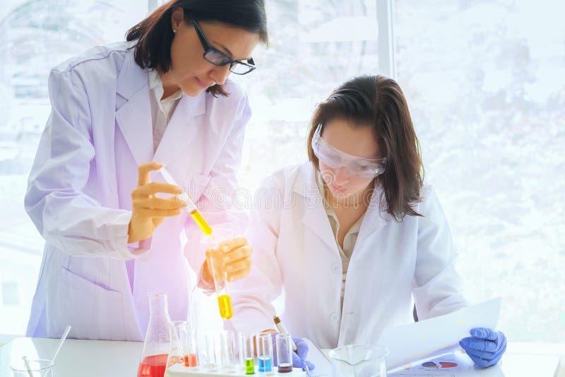 Giovane scienziato femminile che sta con il techer nella fabbricazione del tecnico di laboratorio fotografie stock Giovane scienziato femminile che sta con il techer nella fabbricazione del tecnico di laboratorio fotografie stock