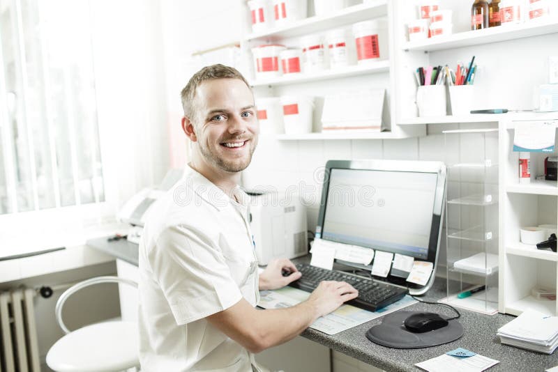 Giovane seduta felice del farmacista fotografia stock libera da diritti Giovane seduta felice del farmacista fotografia stock libera da diritti