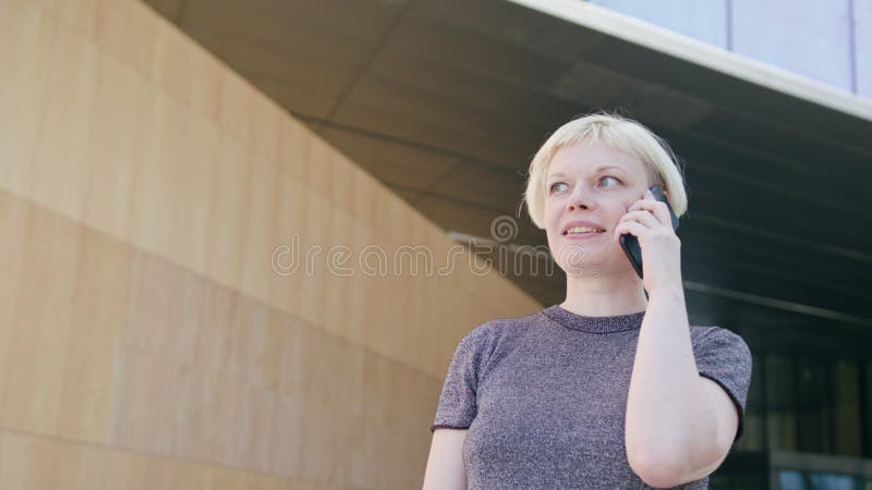 Giovane signora bionda Speaking sul telefono in città fotografia stock libera da diritti Giovane signora bionda Speaking sul telefono in città fotografia stock libera da diritti