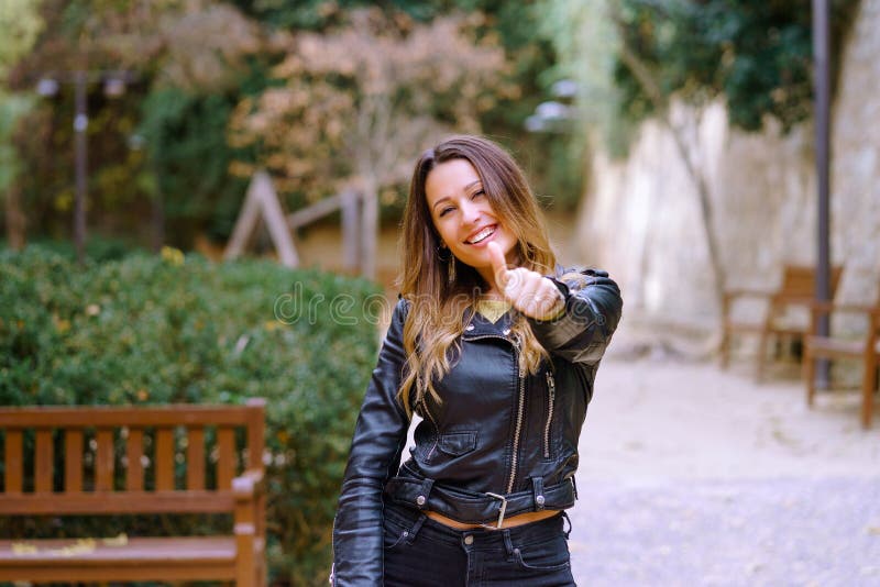 Giovane signora che gesturing pollice su in parco fotografia stock
