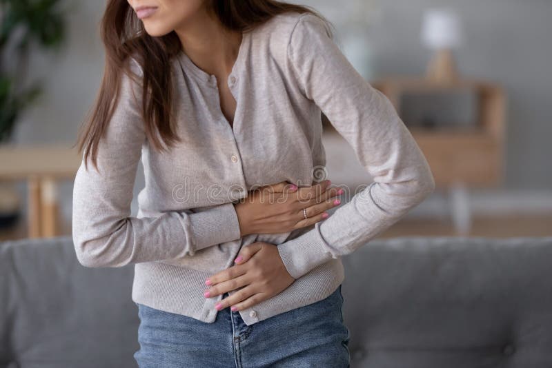 Giovane sofferenza malata della pancia della tenuta di condizione della donna dal mal di stomaco fotografie stock libere da diritti Giovane sofferenza malata della pancia della tenuta di condizione della donna dal mal di stomaco fotografie stock libere da diritti