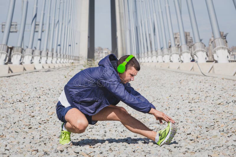Giovane sportivo che allunga le gambe prima del funzionamento di mattina fotografie stock Giovane sportivo che allunga le gambe prima del funzionamento di mattina fotografie stock