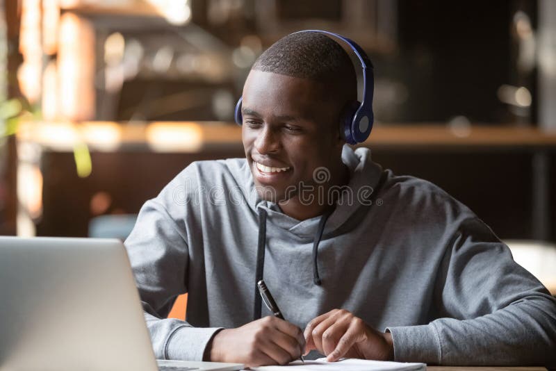 Giovane studente africano sorridente che indossa cuffie studia online