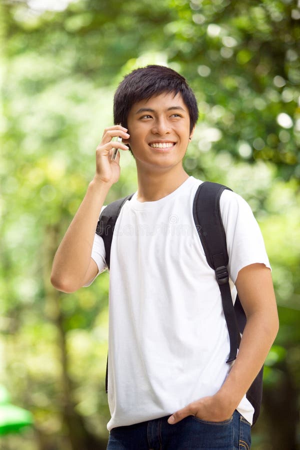 Giovane studente asiatico bello che parla sul telefono cellulare immagini stock libere da diritti Giovane studente asiatico bello che parla sul telefono cellulare immagini stock libere da diritti