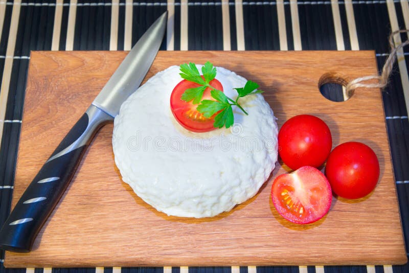 Giovane tagliere del formaggio della quercia con i pomodori ed il prezzemolo Mozarella per le pizze e le insalate fotografie stock Giovane tagliere del formaggio della quercia con i pomodori ed il prezzemolo Mozarella per le pizze e le insalate fotografie stock