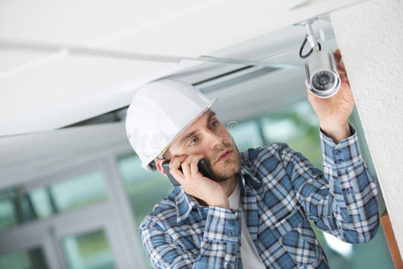 Giovane tecnico che incontra problema mentre regolando la macchina fotografica del cctv fotografia stock libera da diritti Giovane tecnico che incontra problema mentre regolando la macchina fotografica del cctv fotografia stock libera da diritti