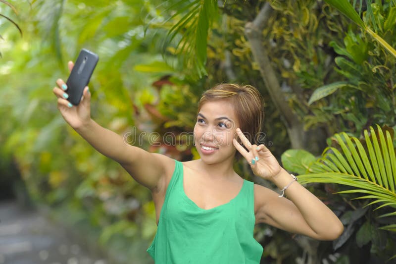 Giovane telefono cellulare dolce ed abbastanza asiatico della tenuta della donna che prende l'immagine del selfie nella posa feli fotografia stock Giovane telefono cellulare dolce ed abbastanza asiatico della tenuta della donna che prende l'immagine del selfie nella posa feli fotografia stock