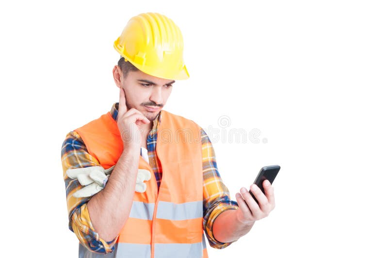 Giovane tenuta pensierosa e lettura del costruttore qualcosa su astuto fotografie stock Giovane tenuta pensierosa e lettura del costruttore qualcosa su astuto fotografie stock