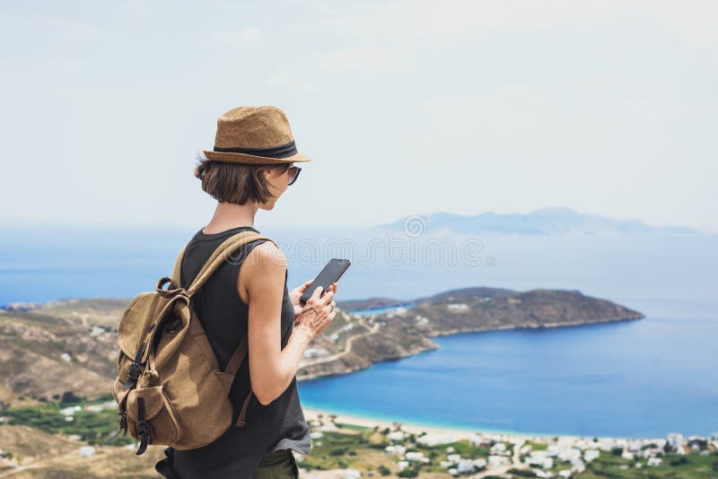 Giovane turista che usa smartphone sul paesaggio con il mare in Grecia Ragazza viaggiatrice con zaino e cellulare fotografia stock