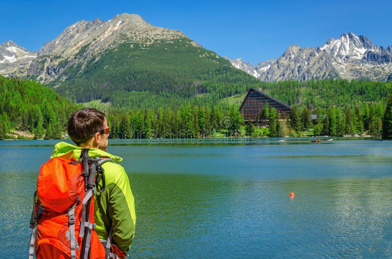 Giovane turista con lo zaino nel lago della montagna fotografie stock Giovane turista con lo zaino nel lago della montagna fotografie stock
