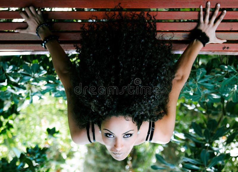Giovane ubicazione africana della donna sul banco in sosta fotografia stock Giovane ubicazione africana della donna sul banco in sosta fotografia stock