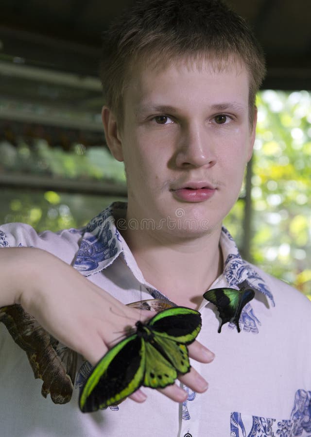 Giovane in un parco delle farfalle con una grande farfalla tropicale fotografie stock