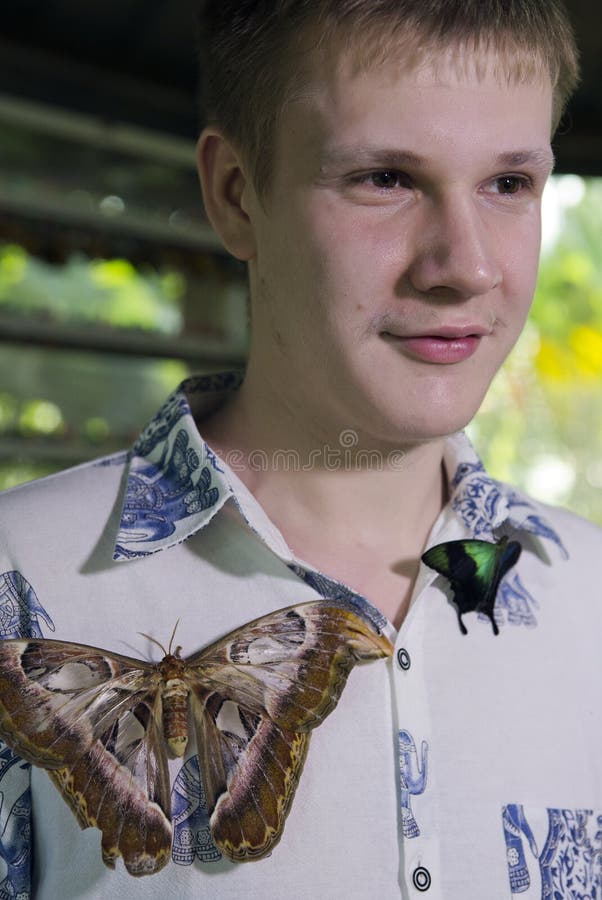 Giovane in un parco delle farfalle con una grande farfalla tropicale immagine stock