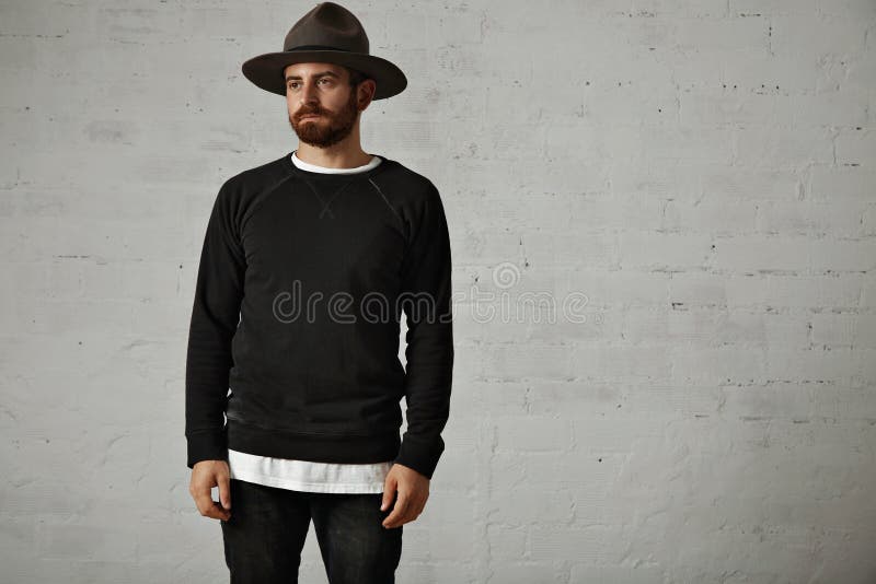 Giovane uomo barbuto in cappello e camicia nera in bianco fotografia stock libera da diritti Giovane uomo barbuto in cappello e camicia nera in bianco fotografia stock libera da diritti