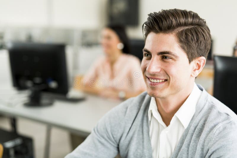 Giovane uomo bello che studia tecnologia dell'informazione in un classroo immagini stock libere da diritti Giovane uomo bello che studia tecnologia dell'informazione in un classroo immagini stock libere da diritti