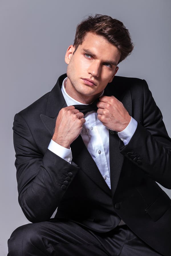 Giovane uomo bello di affari che tira la sua cravatta a farfalla fotografie stock Giovane uomo bello di affari che tira la sua cravatta a farfalla fotografie stock