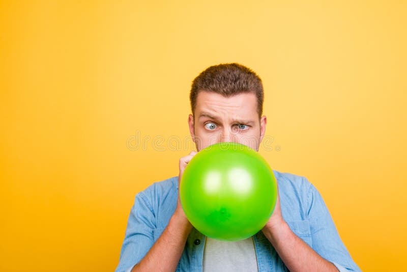 Giovane uomo biondo attraente stanco fare scoppiare PA del nuovo anno dei palloni immagine stock libera da diritti Giovane uomo biondo attraente stanco fare scoppiare PA del nuovo anno dei palloni immagine stock libera da diritti