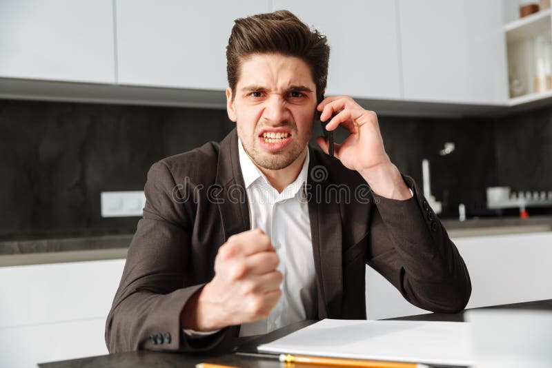Giovane uomo d'affari arrabbiato che parla dal telefono cellulare fotografia stock Giovane uomo d'affari arrabbiato che parla dal telefono cellulare fotografia stock