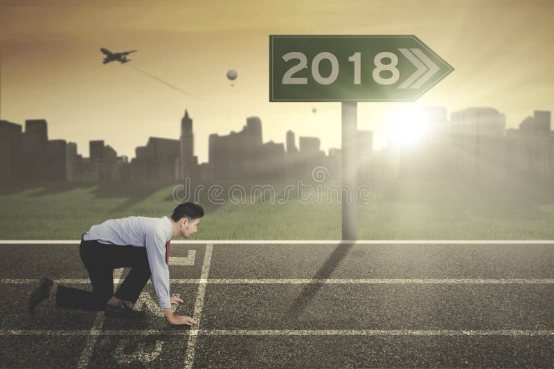Giovane uomo d'affari con i numeri 2018 sul cartello immagine stock Giovane uomo d'affari con i numeri 2018 sul cartello immagine stock