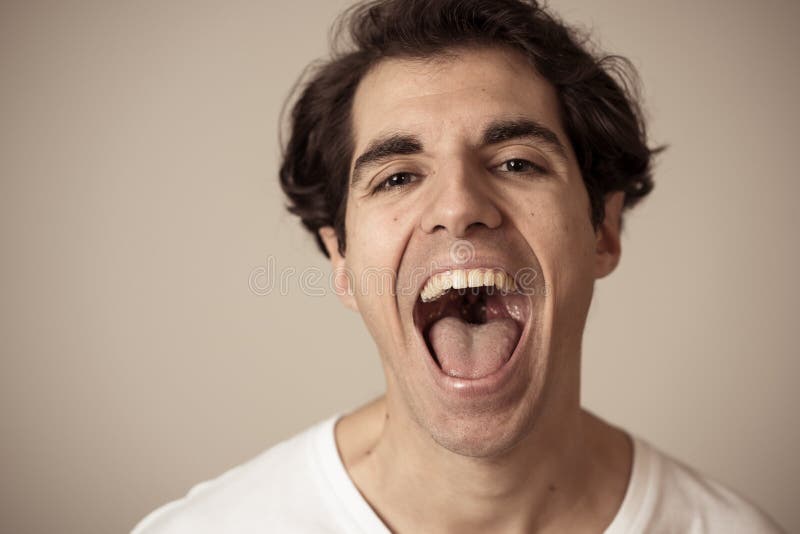 Giovane uomo divertente positivo ed allegro nei suoi anni venti che ride e che si diverte duro fotografia stock libera da diritti Giovane uomo divertente positivo ed allegro nei suoi anni venti che ride e che si diverte duro fotografia stock libera da diritti
