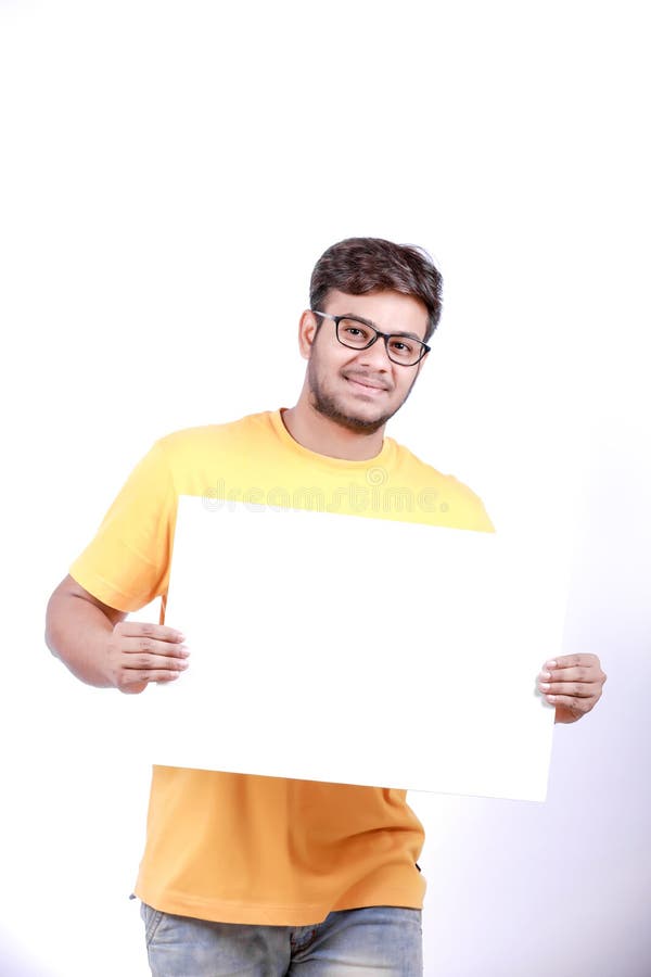 Giovane uomo indiano emozionante sugli occhiali e sulla mostra del manifesto in bianco a disposizione fotografia stock libera da diritti Giovane uomo indiano emozionante sugli occhiali e sulla mostra del manifesto in bianco a disposizione fotografia stock libera da diritti