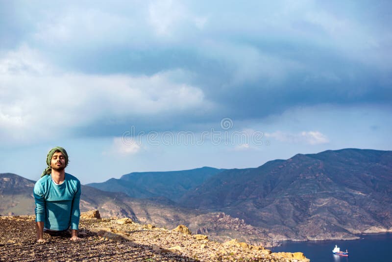 Giovane uomo indiano sulla roccia della scogliera del bordo superiore della collina che esegue yoga immagini stock libere da diritti Giovane uomo indiano sulla roccia della scogliera del bordo superiore della collina che esegue yoga immagini stock libere da diritti
