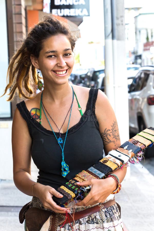 Itajai, Santa Catarina, Brazil - February 22th, 2018: A female brazilian street bracelets vendor, with tatoo and piercing in her face smiling at streets near the Port of Itajai. Itajai, Santa Catarina, Brazil - February 22th, 2018: A female brazilian street bracelets vendor, with tatoo and piercing in her face smiling at streets near the Port of Itajai.