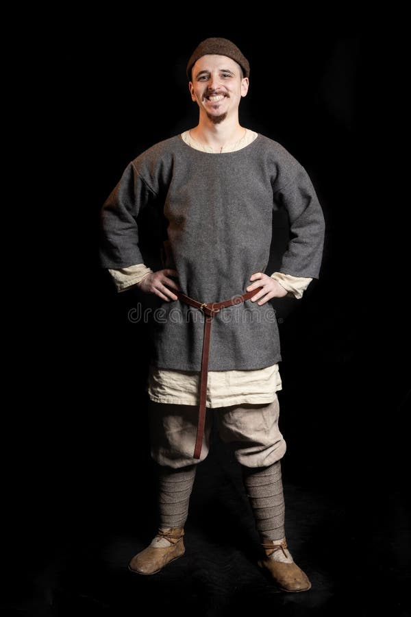 Giovane in vestiti grigi casuali ed in un cappello dei sorrisi iniziali di medio evo di Viking Age fotografia stock Giovane in vestiti grigi casuali ed in un cappello dei sorrisi iniziali di medio evo di Viking Age fotografia stock