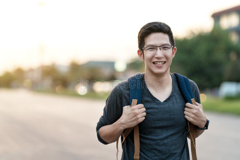 Giovane zaino asiatico attraente della tenuta del tipo dell'istituto universitario o dell'uomo che sorride alla vacanza di sensib fotografia stock libera da diritti Giovane zaino asiatico attraente della tenuta del tipo dell'istituto universitario o dell'uomo che sorride alla vacanza di sensib fotografia stock libera da diritti