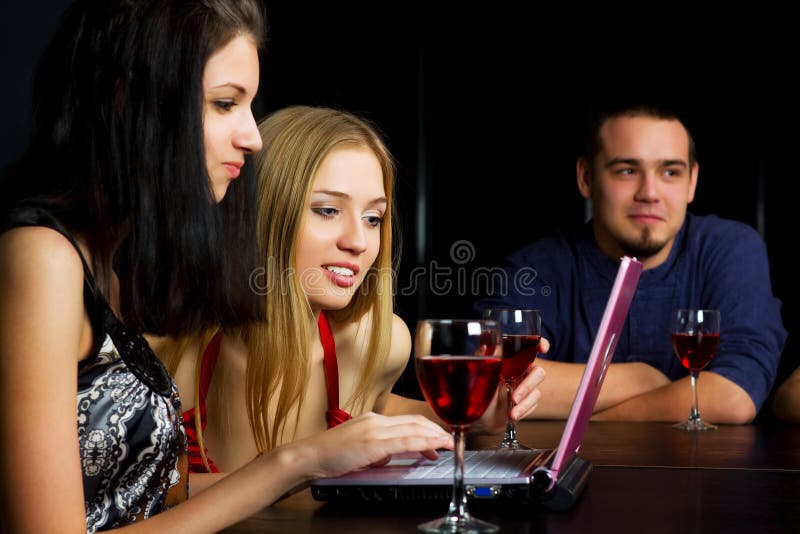 Giovani amici con un laptop in un bar immagini stock