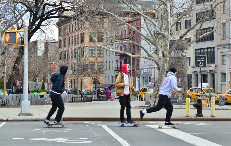 Giovani bambini dei pantaloni a vita bassa che guidano pattino nella città del Lower East Side di New York delle vie della città fotografia stock Giovani bambini dei pantaloni a vita bassa che guidano pattino nella città del Lower East Side di New York delle vie della città fotografia stock