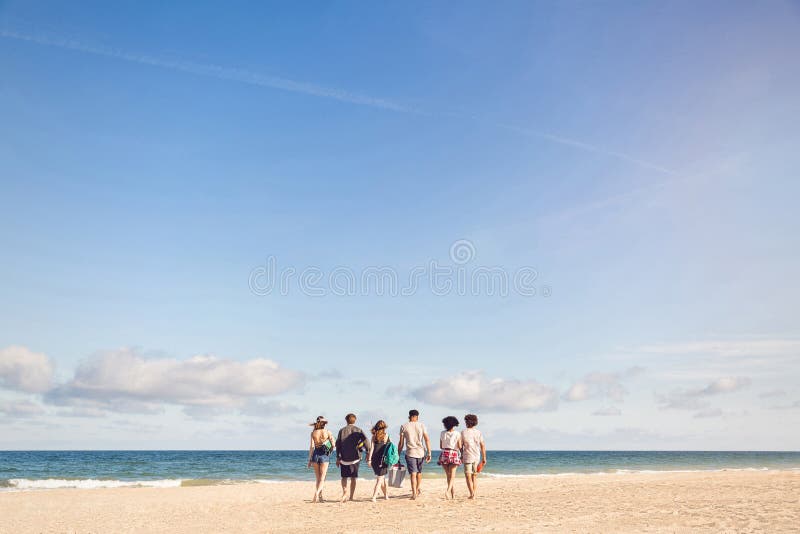 Giovani che camminano sulla spiaggia che porta una scatola più fresca immagine stock libera da diritti Giovani che camminano sulla spiaggia che porta una scatola più fresca immagine stock libera da diritti