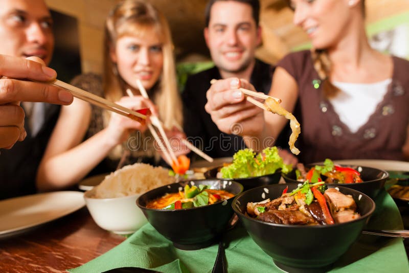 Giovani che mangiano nel ristorante tailandese fotografia stock libera da diritti Giovani che mangiano nel ristorante tailandese fotografia stock libera da diritti