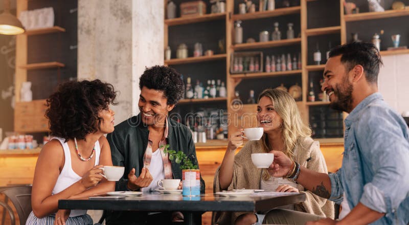 Giovani che si siedono ad una caffetteria immagine stock
