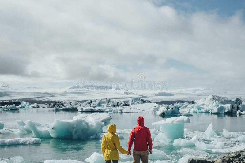 Giovani coppie alla moda in Islanda vicino alla laguna glaciale immagini stock libere da diritti Giovani coppie alla moda in Islanda vicino alla laguna glaciale immagini stock libere da diritti
