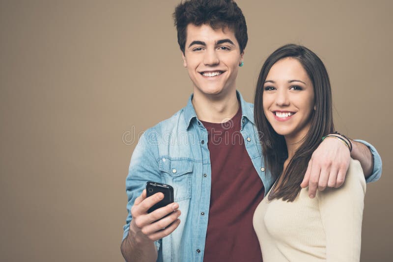 Giovani coppie allegre con il telefono cellulare fotografie stock libere da diritti Giovani coppie allegre con il telefono cellulare fotografie stock libere da diritti