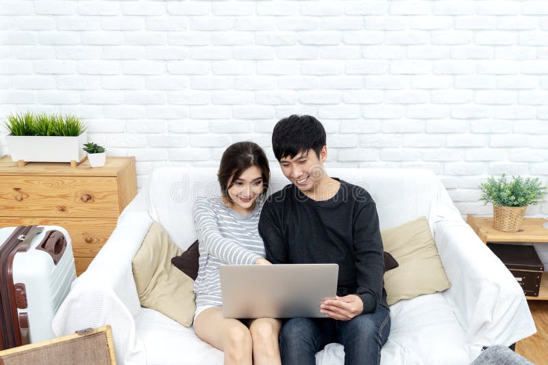 Giovani coppie asiatiche che esaminano computer portatile per cercare il programma di corsa, la camera di albergo del libro, il b immagine stock libera da diritti Giovani coppie asiatiche che esaminano computer portatile per cercare il programma di corsa, la camera di albergo del libro, il b immagine stock libera da diritti