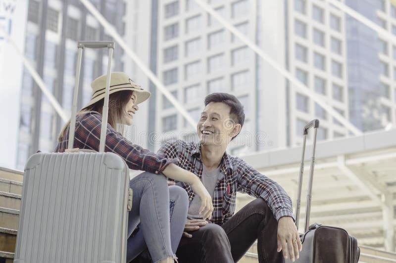 Giovani coppie asiatiche dei viaggiatori che sorridono felicemente mentre sedendosi i wi fotografia stock libera da diritti Giovani coppie asiatiche dei viaggiatori che sorridono felicemente mentre sedendosi i wi fotografia stock libera da diritti