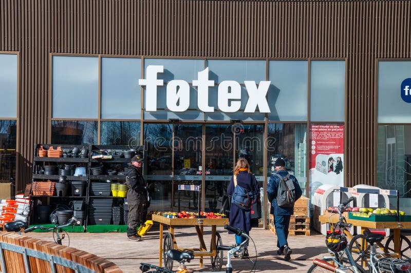 Giovani coppie che camminano verso un supermercato e un senzatetto che vende un giornale fotografie stock Giovani coppie che camminano verso un supermercato e un senzatetto che vende un giornale fotografie stock