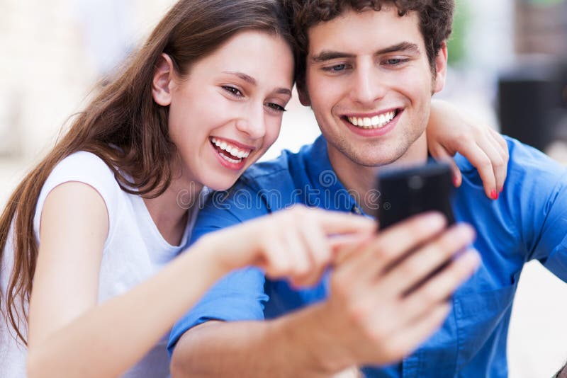 Giovani coppie che esaminano telefono cellulare Giovani coppie che esaminano telefono cellulare