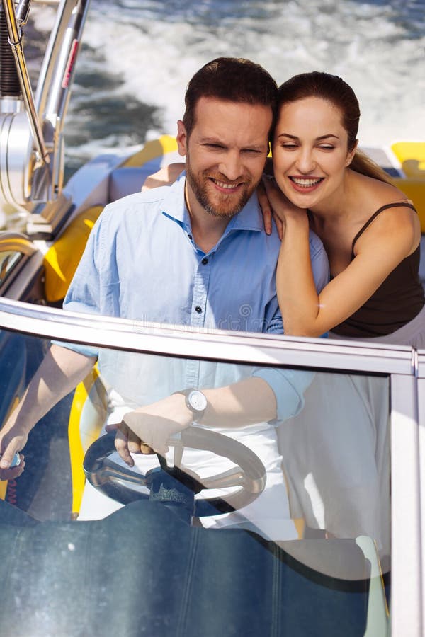 Giovani coppie felici che godono del giro sul loro yacht fotografia stock libera da diritti Giovani coppie felici che godono del giro sul loro yacht fotografia stock libera da diritti