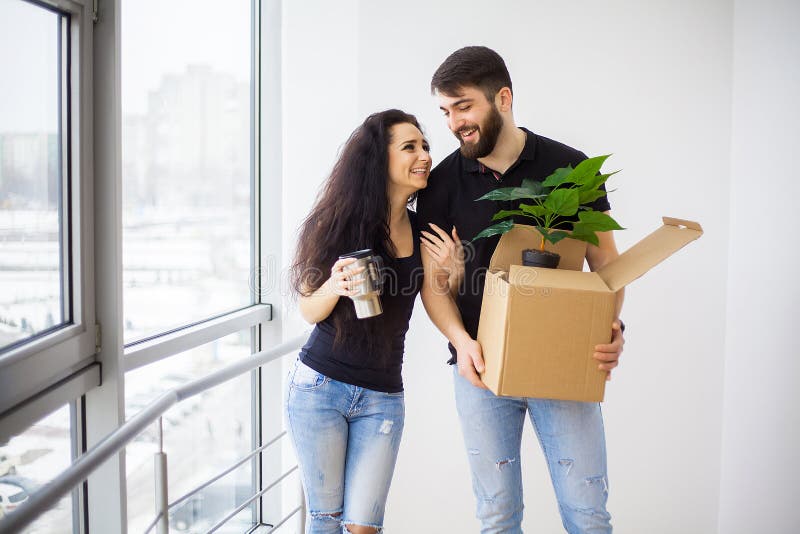 Giovani coppie felici che si muovono nella nuova casa che disimballa le scatole immagini stock