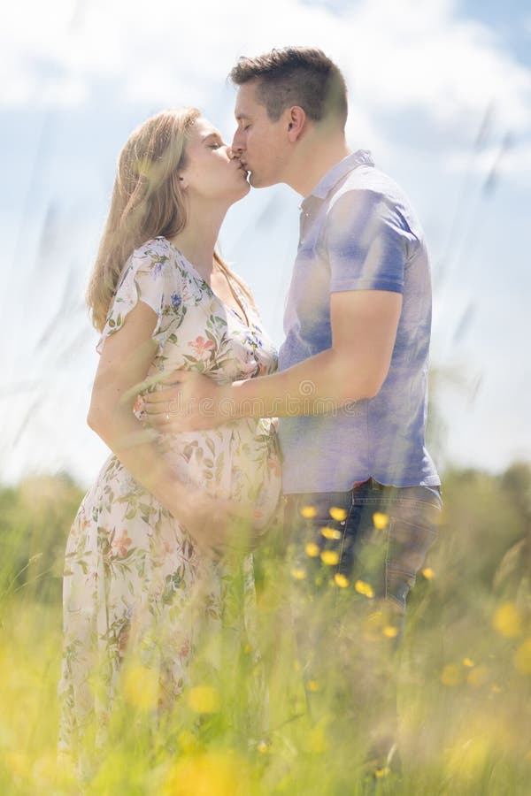 Giovani coppie incinte felici nel tenersi per mano di amore, rilassantesi nel prato fotografia stock Giovani coppie incinte felici nel tenersi per mano di amore, rilassantesi nel prato fotografia stock