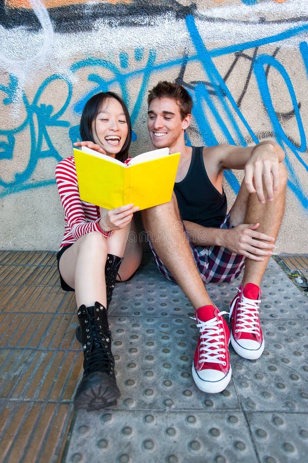 Giovani coppie multi-etniche che leggono un libro immagini stock Giovani coppie multi-etniche che leggono un libro immagini stock